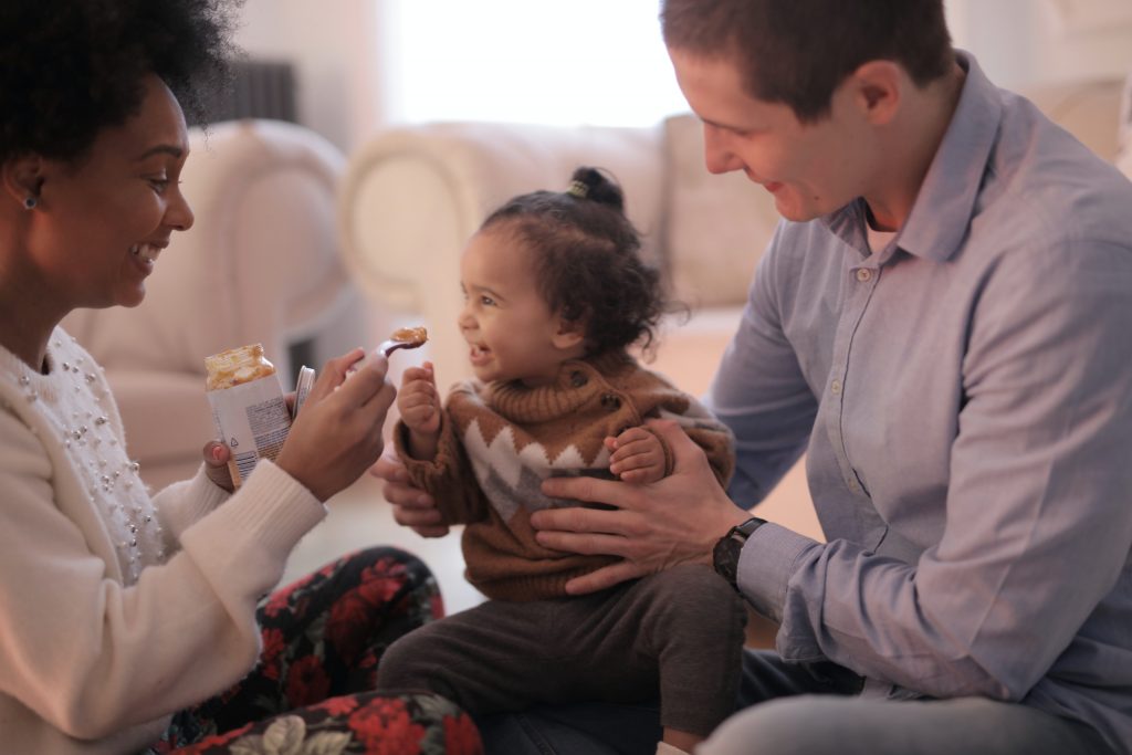 Enfant avec ses parents mangeant un petit pot lors d'une séance photo