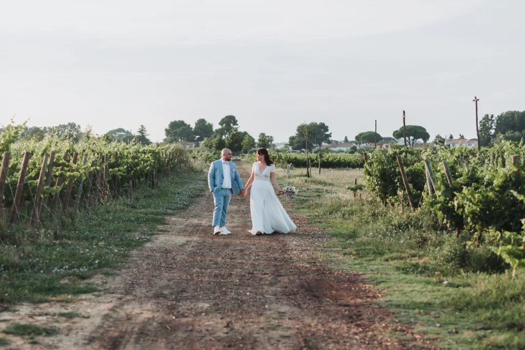 Couple de mariés marchant le long d'un chemin entourés de vignes